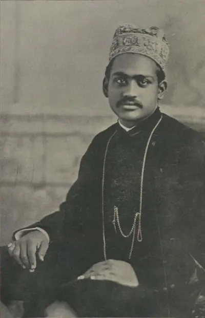 Raja Ramasor Row II seated, in an embroidered cap and dark coat with a watch chain.