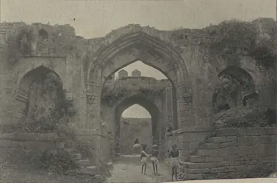 The Hyderabad Gate of Warangal, a ruined arched gateway, with people in the passage.