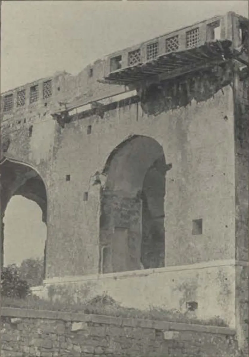 A ruined palace wall with a large arch and a balcony.