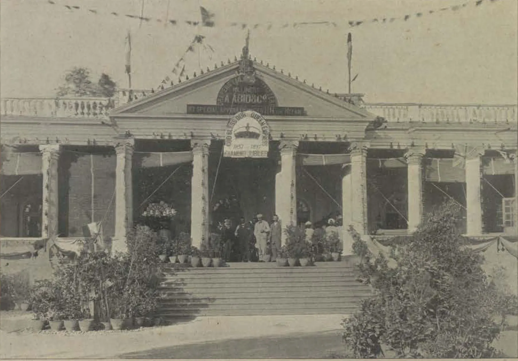 A classical shop front with a portico, decorated with flags.