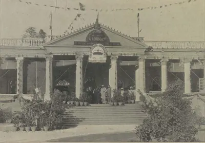 A classical shop front with a portico, decorated with flags.