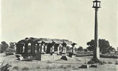 A ruined Vishnu temple at Nagunur with a pillared hall and a tall lamp pillar beside it.