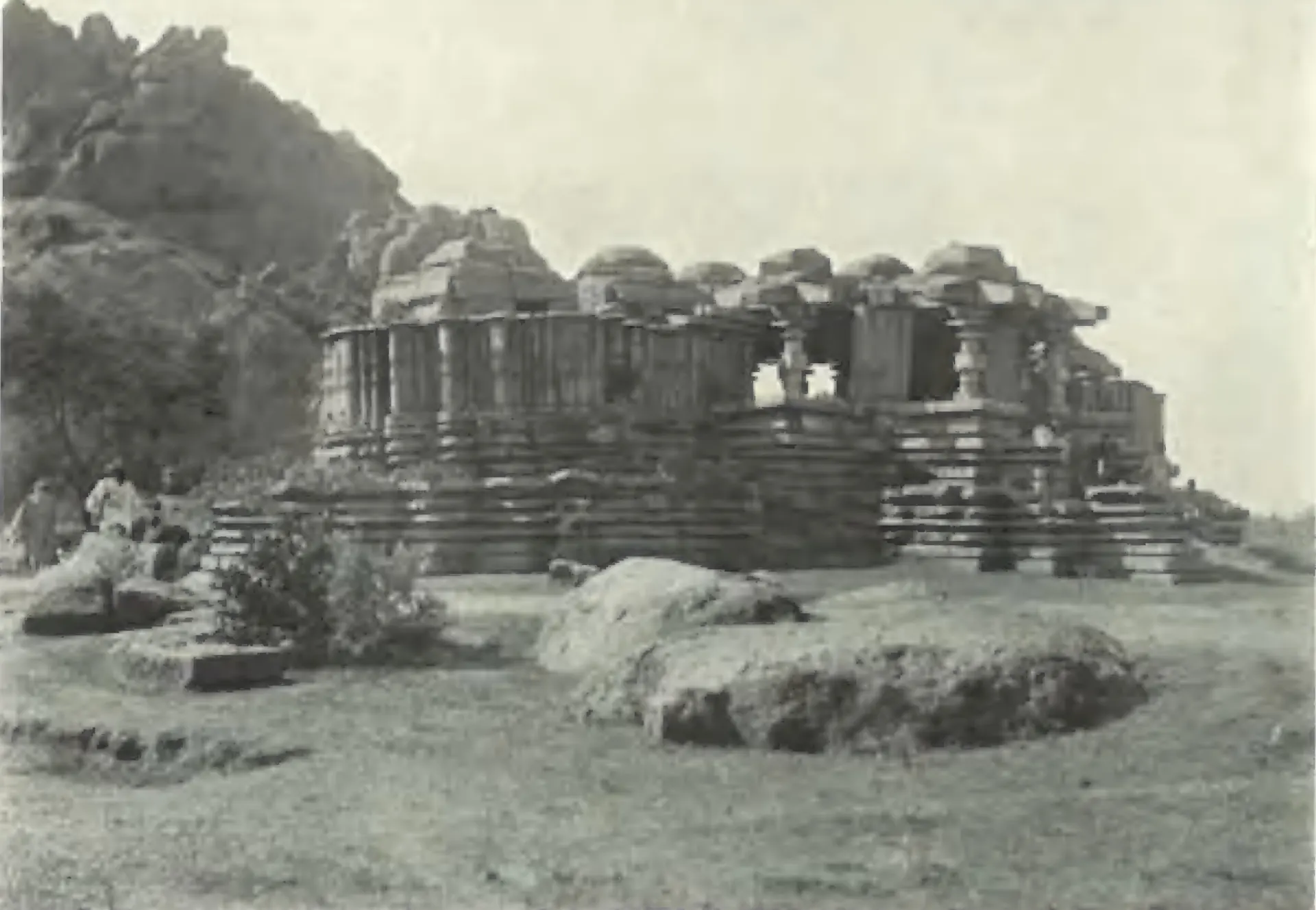 The Siva temple at Nagunur, a ruined temple on a platform below a rocky hill.