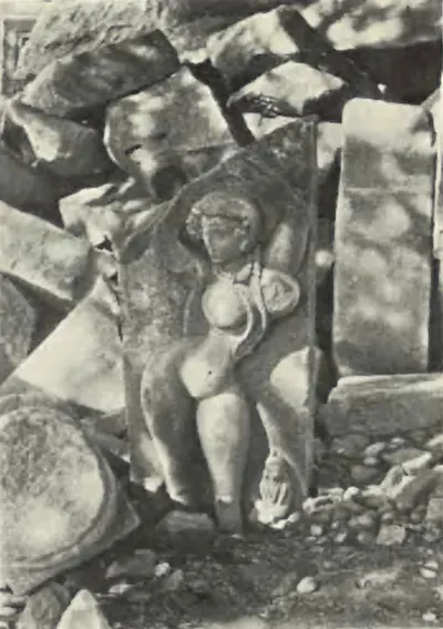 A carved figure on a fallen stone slab among broken stones at Pedampet.