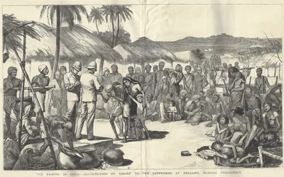 Wood engraving of a famine relief camp under palm trees and thatched huts, two Europeans in sun helmets supervising the distribution of food to a crowd of emaciated men, women and children, some lying on the ground.