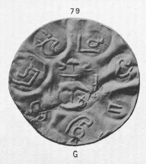 Photograph of a large, thin, wrinkled gold coin with several round punch-marks of letters and small emblems around a central mark; the plate number 79 above and the letter G (gold) below.