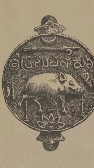 Engraving of a round seal with a knob at top and bottom: a boar walking to the right under a line of letters, an elephant goad and a crescent, with lamps at the sides and a lotus below.