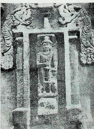 A wall niche framed by pilasters and curling makara ornament, holding a standing figure identified in the caption as Indra.