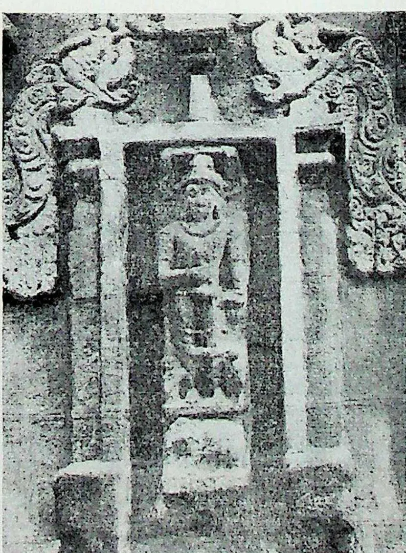 A wall niche framed by pilasters and curling makara ornament, holding a standing figure identified in the caption as Indra.