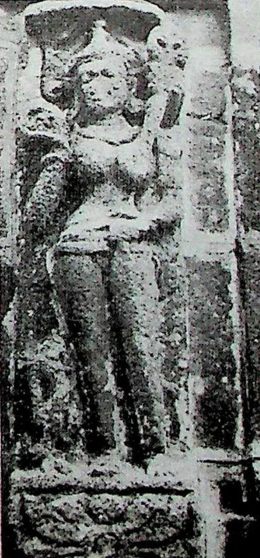 A narrow upright relief of a standing female figure with a tall headdress, in a gentle hip-shot pose.