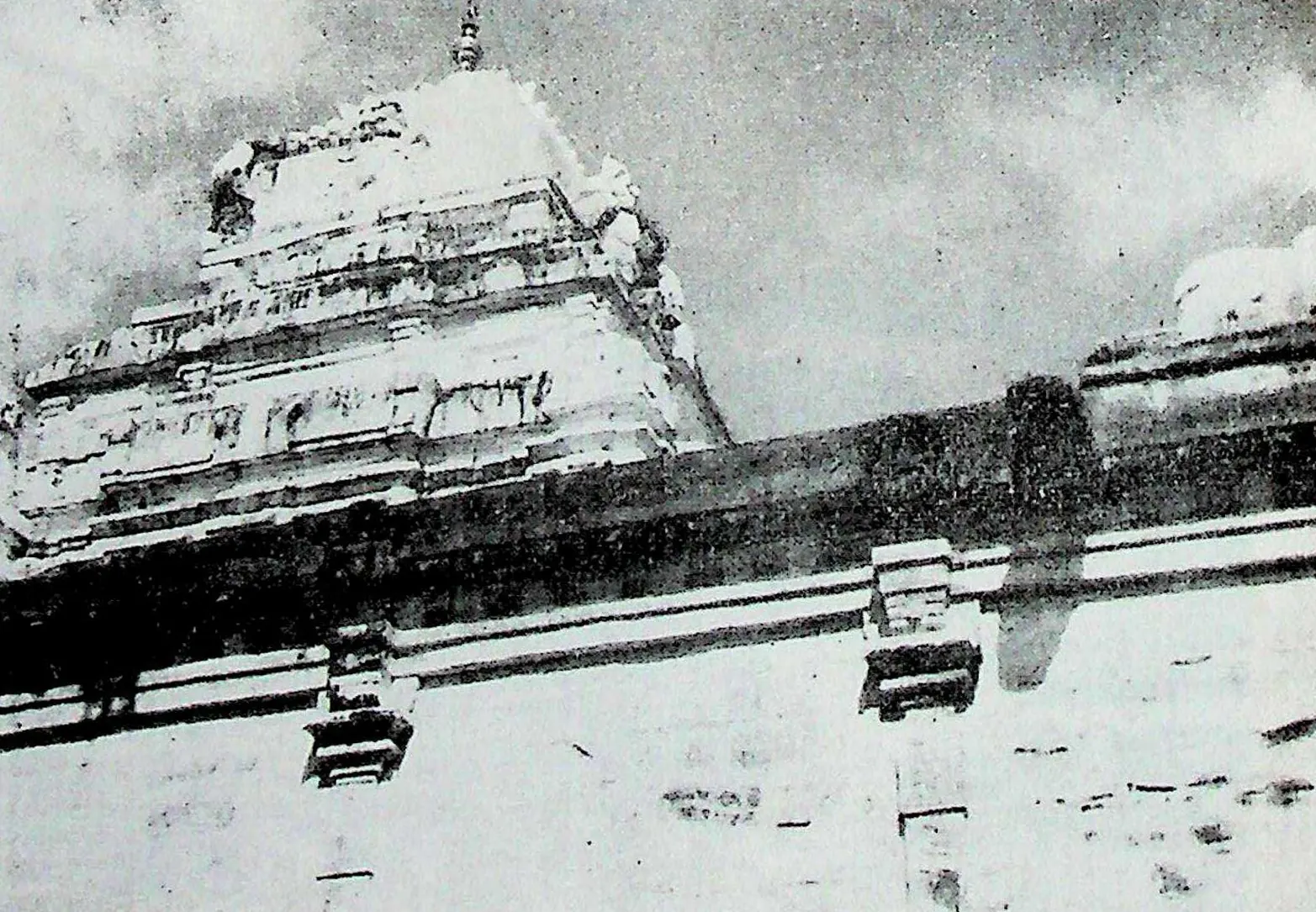 The upper part of the main shrine tower rising above a long sloping roofline, seen from a low angle against the sky.