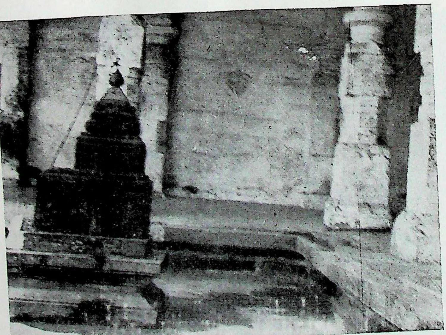 A miniature shrine with a pointed tower set against a large plain wall and pillars, inside the Bhimesvara temple at Chalukya Bhimavaram (Samalkot).