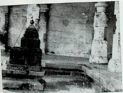 A miniature shrine with a pointed tower set against a large plain wall and pillars, inside the Bhimesvara temple at Chalukya Bhimavaram (Samalkot).