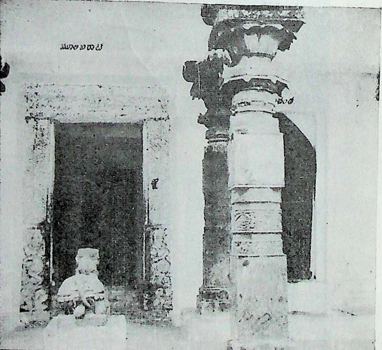 A pillared pavilion with an ornate turned stone column and a doorway, a small Nandi image inside.
