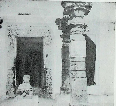 A pillared pavilion with an ornate turned stone column and a doorway, a small Nandi image inside.