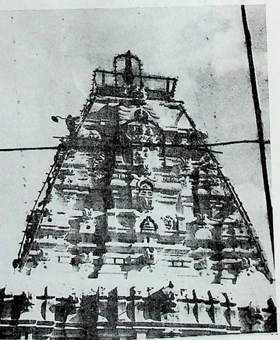 A tall pyramidal tower of many tiers covered with small figures and roof mouldings, with wires crossing in front.