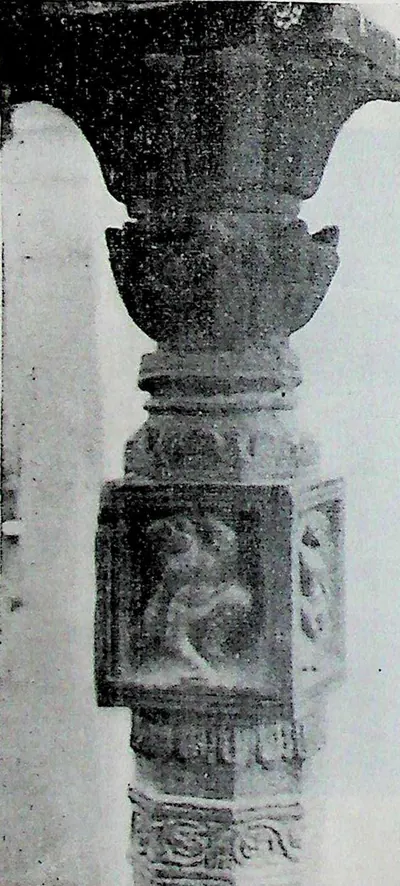 A carved stone pillar with a bracket capital, a square panel holding a small figure and banded mouldings below.