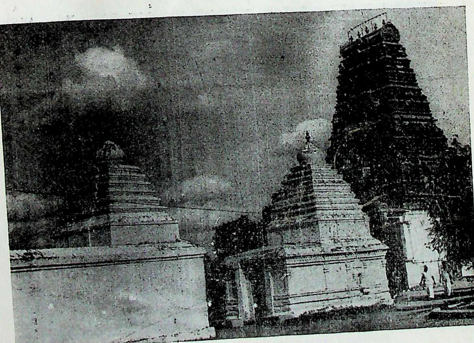 Small shrines with stepped towers inside the outer enclosure at Amaravati, a tall gateway tower behind at the right.
