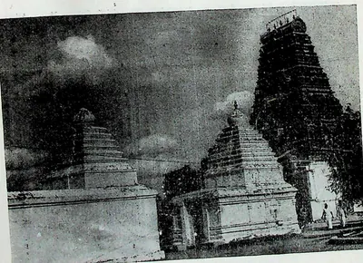 Small shrines with stepped towers inside the outer enclosure at Amaravati, a tall gateway tower behind at the right.