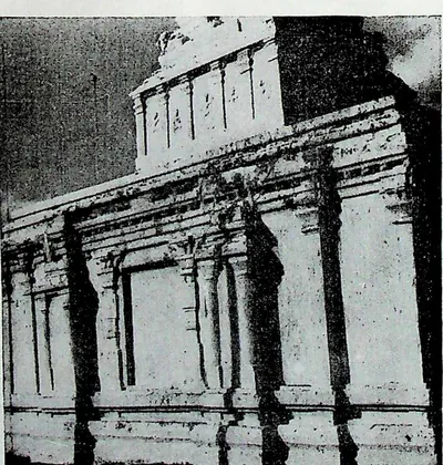 A whitewashed temple wall of pilasters and niches under a heavy cornice, with a small tower above, seen in strong light and shadow.