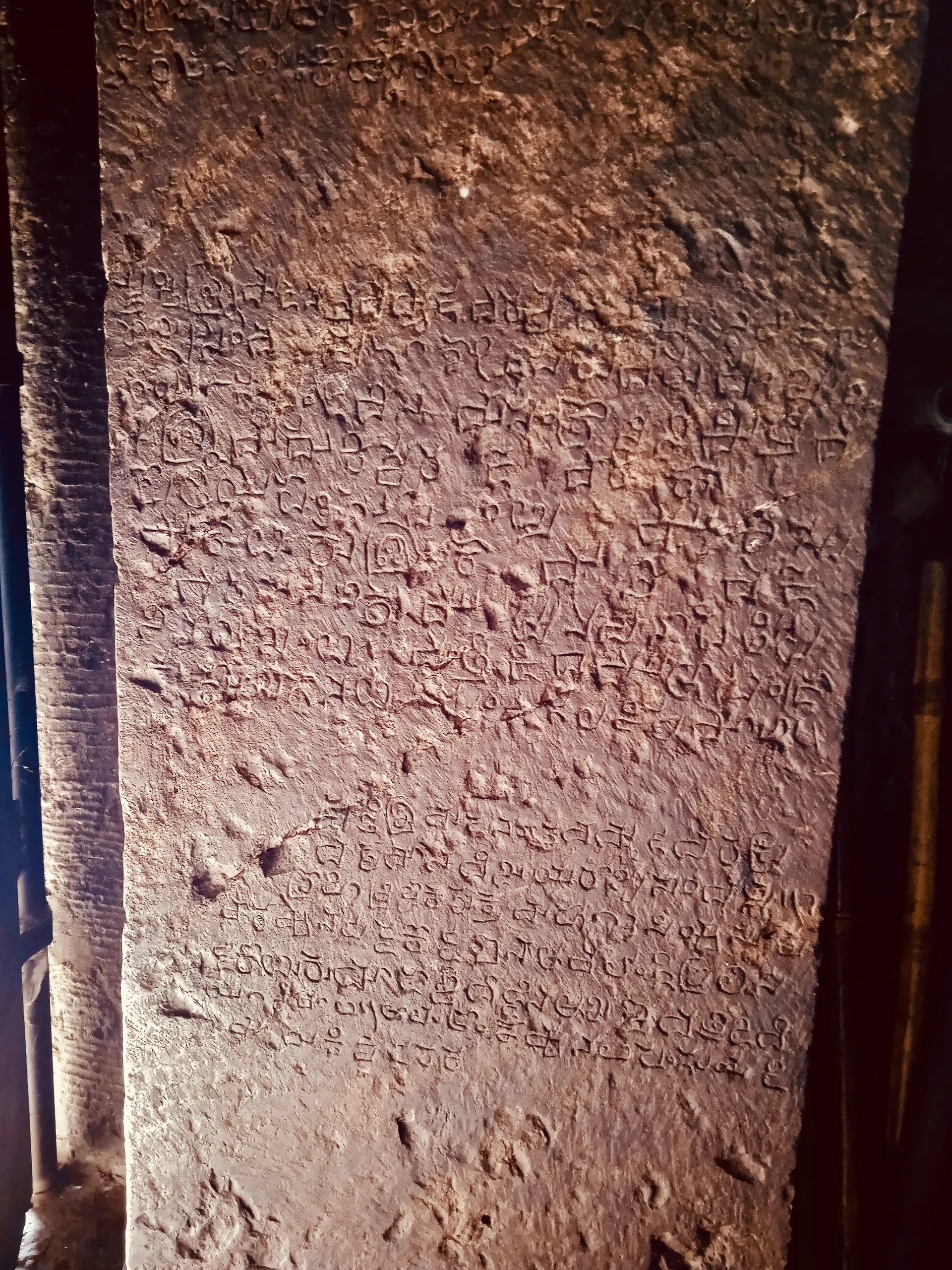 Colour photograph of a weathered stone wall face covered with rows of small, worn inscribed letters.