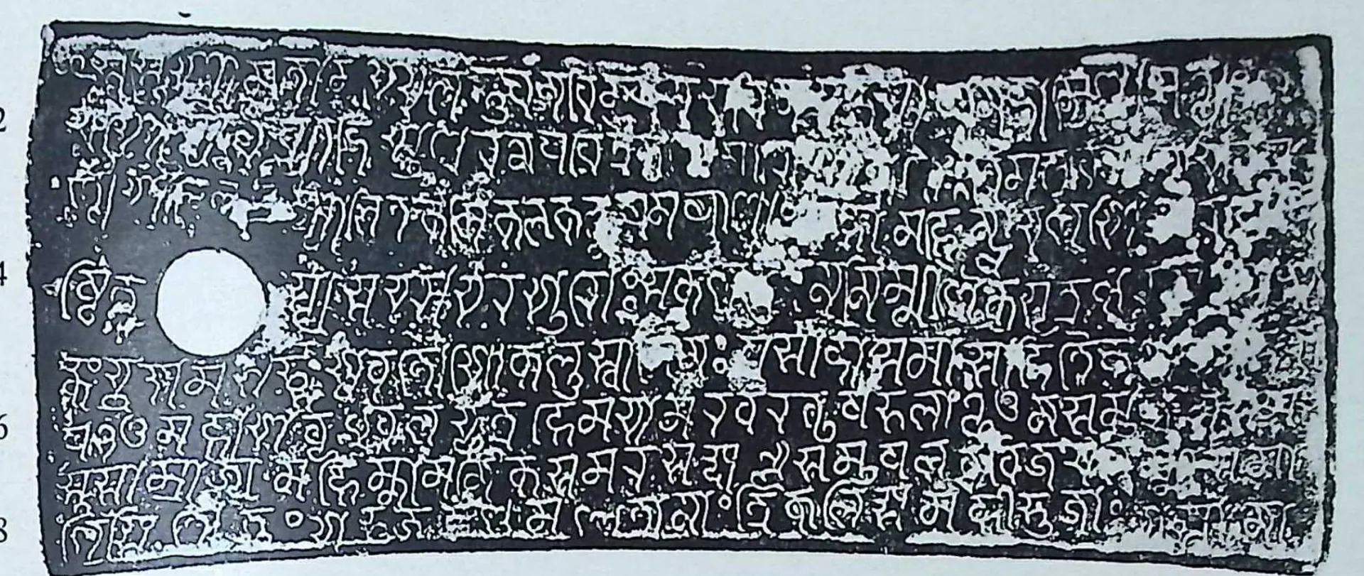 Ink impression of one wide copper-plate face: eight lines of Nagari-influenced Kalinga letters, faint in places, a white ring-hole at the left, line numbers in the right margin.