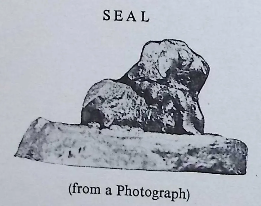 Photograph of a copper-plate seal seen obliquely from the side: a seated bull in relief standing up from a flat, round base.