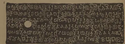 Lithograph of one copper-plate face, white letters on a dark grey ground: six lines of box-headed Kalinga-script letters with a white ring-hole at the left.
