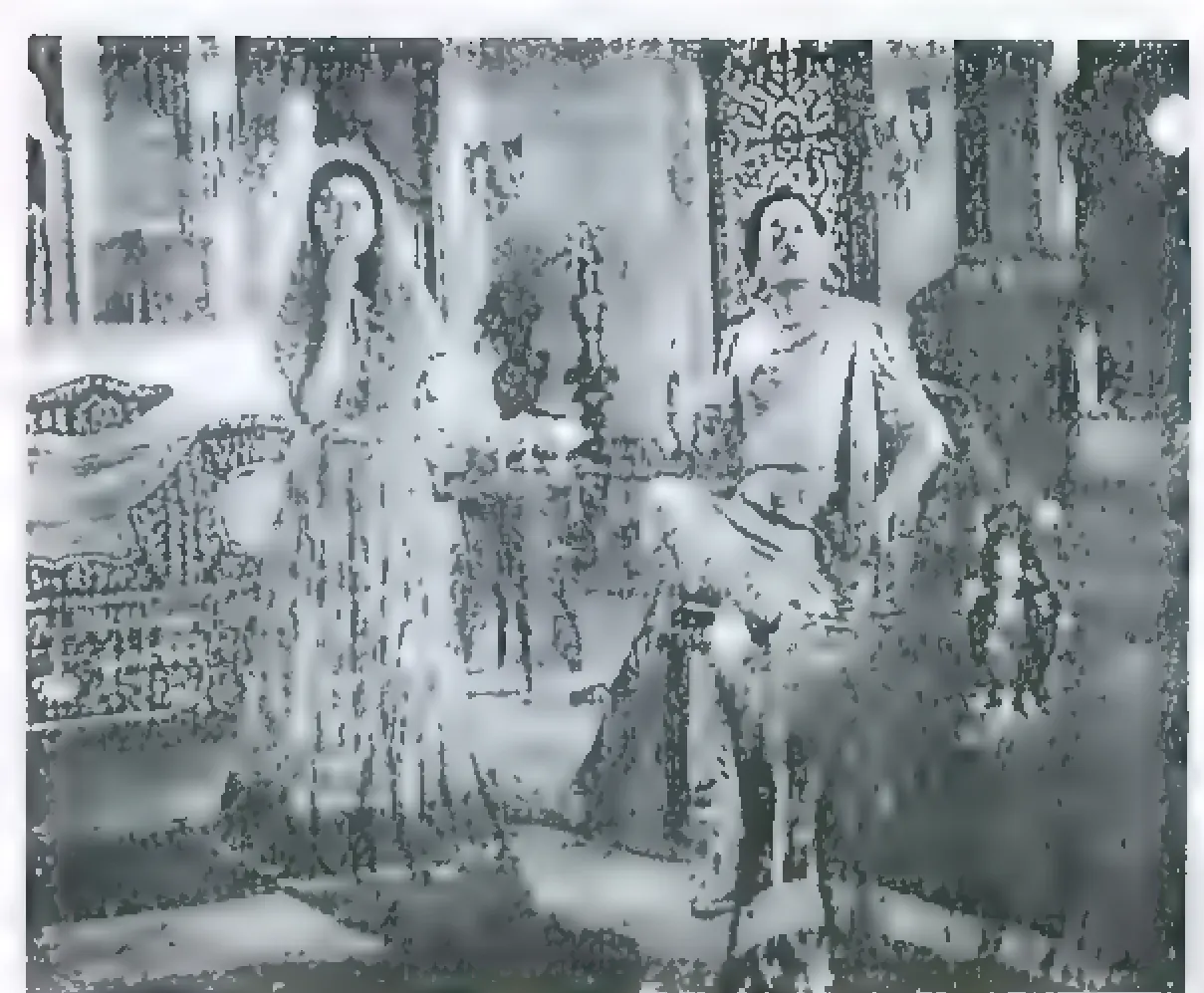 Black-and-white film still of a woman in a sari standing with a hand at her face, and a man seated on a carved chair in a decorated room.