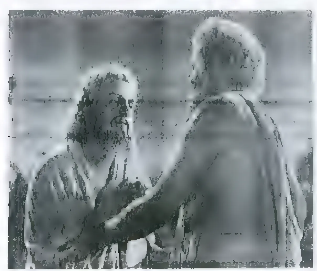 Black-and-white film still of a bearded man in a robe, seen from the side, facing an older man with white hair who puts a hand on his shoulder.