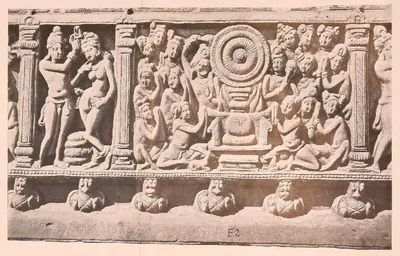 Carved frieze panel with a large wheel on a throne and kneeling worshippers.