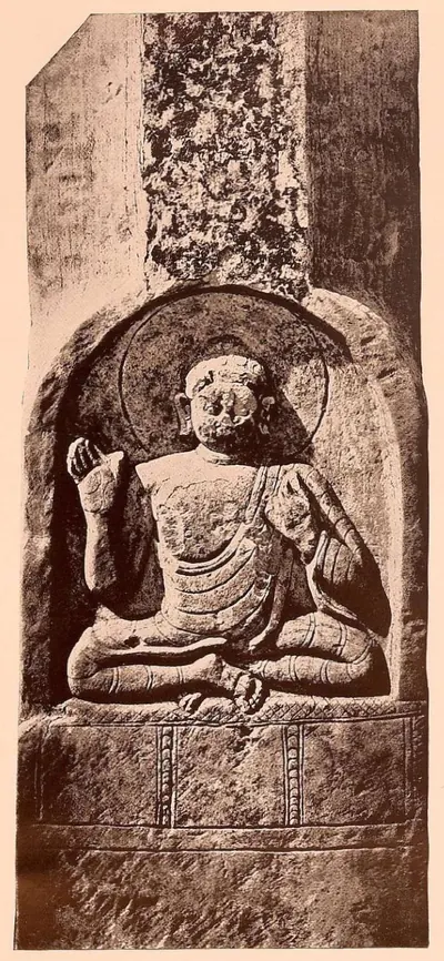 Carved limestone pillar with a seated Buddha in an arched niche.