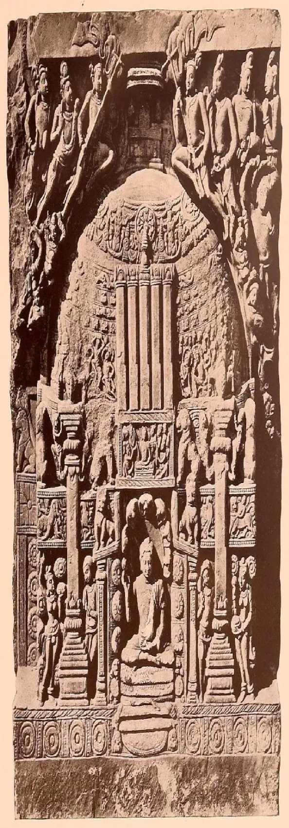 Tall carved slab showing a domed stupa decorated in bands, with figures and a seated Buddha below.