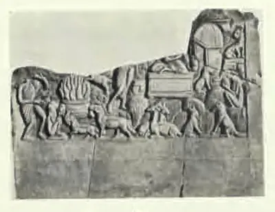 A broken carved slab with a frieze of small animals and human figures, a heap of flames at the left, a box-like seat in the middle and an arched hut at the upper right; the lower half of the stone is plain.