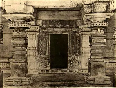 A carved shrine doorway between two heavy lathe-turned pillars inside the temple.