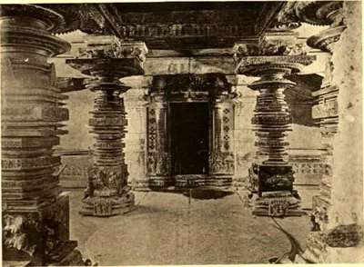 A dark shrine doorway framed by carved jambs between two heavy turned pillars.