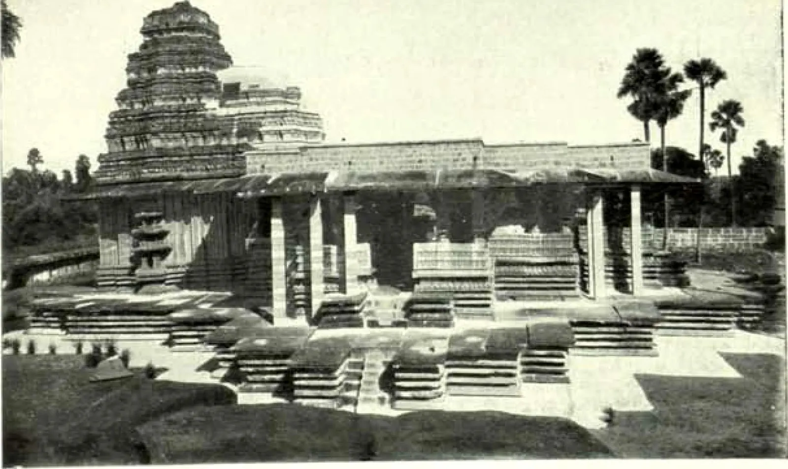 The Ramappa temple after repair: a pillared hall on a stepped platform with the stepped tower behind and palm trees at the right.
