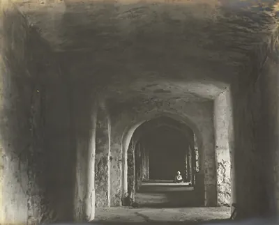 A long vaulted passage inside the ruined palace, with arched openings along both sides and a person standing at the far end.
