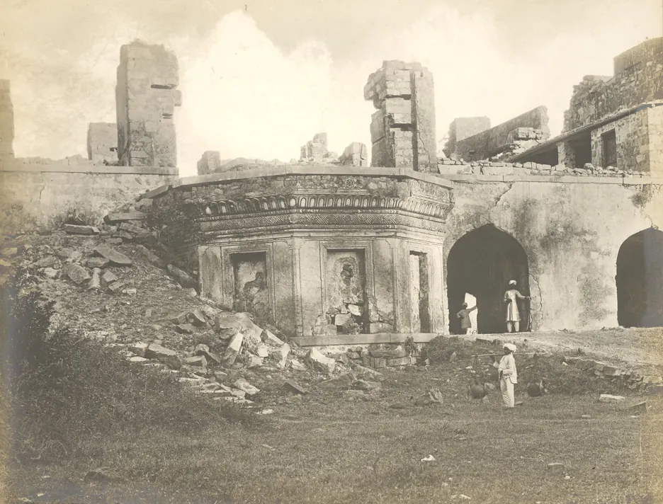 The ruined palace at Kondapalli: a raised stone platform with arched openings in front of broken walls, with people standing on and below it.