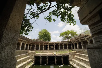 Inside a deep square stepwell: rows of stone pillars carry galleries on several levels, with stone steps leading down to water.