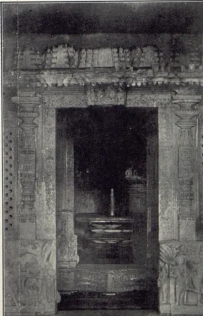 A carved shrine doorway with pierced screens at the sides, and a linga on its pedestal visible in the dark sanctum beyond.