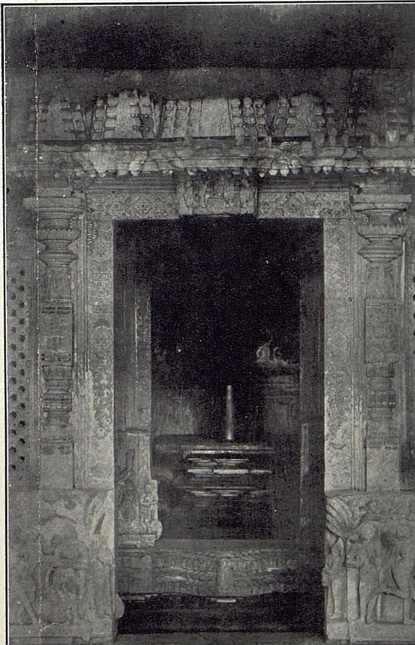 A carved shrine doorway with pierced screens at the sides, and a linga on its pedestal visible in the dark sanctum beyond.