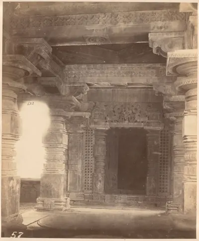 Inside the Thousand Pillar Temple: a dark shrine doorway framed by carved jambs and a heavy carved lintel, between turned and carved pillars, with a pierced stone screen letting in light at the left.