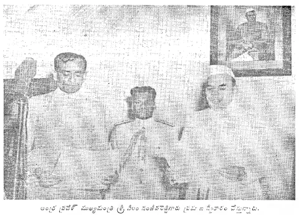 A grainy black-and-white photograph of three men standing in a room, the man on the left in a white coat reading from a paper at a microphone, an officer in uniform in the middle, and a framed portrait on the wall behind.