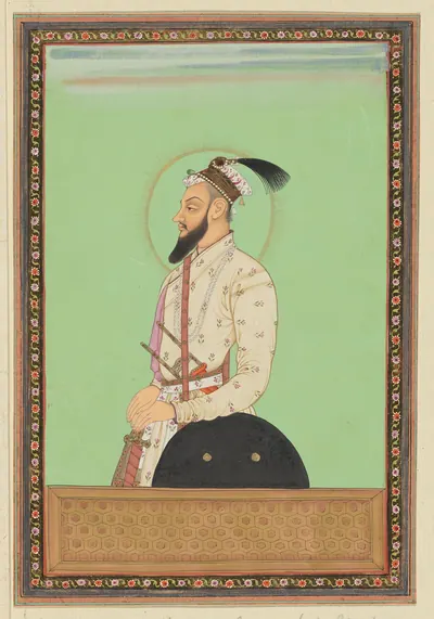 Deccani painting of a bearded man in a white patterned robe with a sword and shield, standing in profile with a halo against a green ground, in a decorated border.