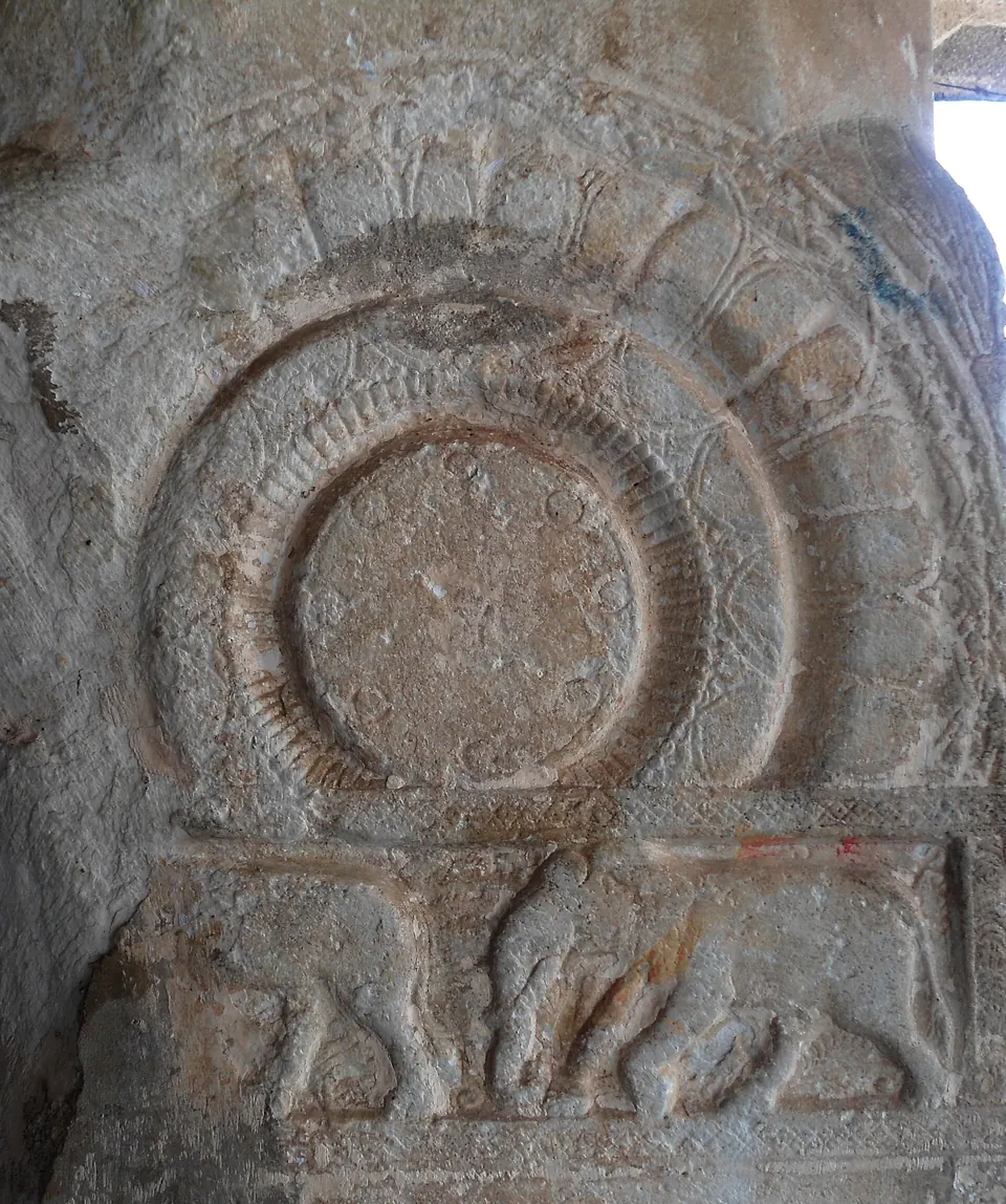 A grey marble pillar carved with a large round lotus medallion above a band with small animal figures.