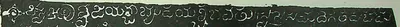Detail of an ink impression: one line of white Telugu-Kannada letters on a black ground, beginning with an ornamental sign.