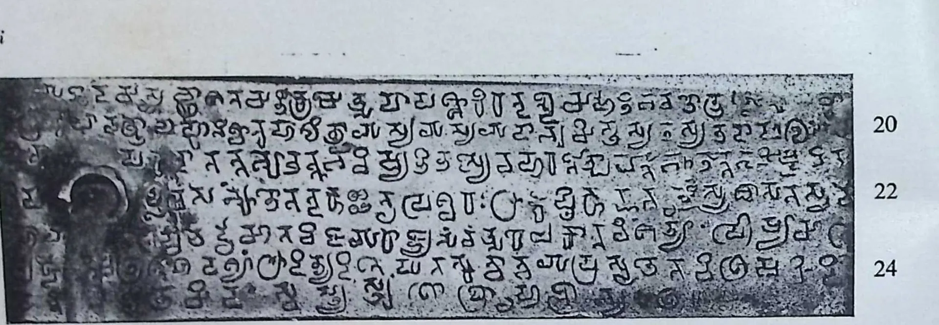 Photograph of one inscribed copper plate on its ring, six lines of Pallava-Grantha script with line numbers 20 to 24.