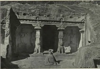 Halftone photograph of a rock-cut shrine front with two pillars carved with seated lions at their bases, a carved cornice above, and a seated stone bull on the terrace in front.