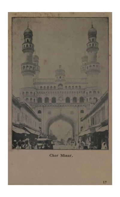Photograph of the Char Minar seen down a street, its four minarets rising above the arched central block, with shops and people in the foreground.